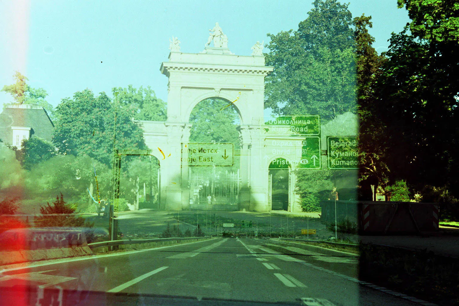 double exposure and greenish picture of a higway leading to some arc de triumph like gate. we can see street signs with cyrillic words