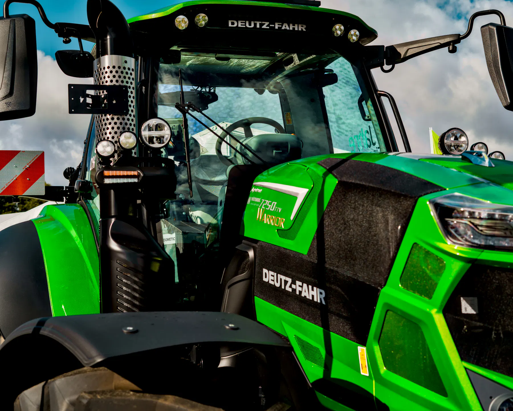 Nahaufnahme eines Deutz Traktors 7250 in grünmetallic Lackierung. Die Maschine sieht beeindruckend aus - groß, kraftvoll und schwer. 
Aber mit einer so teuren Lackierung auf das Feld? Eher nicht! Ist wohl eher ein Kundenfänger.